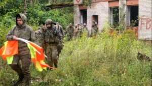 Участники хардбольной игры проходят мимо заброшенного здания с сигнальными флажками.