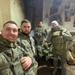 Четверо участников в защитной экипировке фотографируются в помещении.