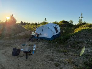 Палатка и походный стол на лесном полигоне.