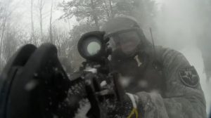 Участник в защитной экипировке целится из оружия сквозь дым или туман.